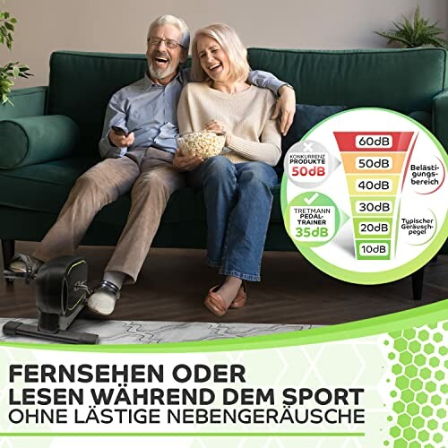 Älteres Paar sitzt auf dem Sofa, schaut fern und benutzt einen Pedaltrainer.