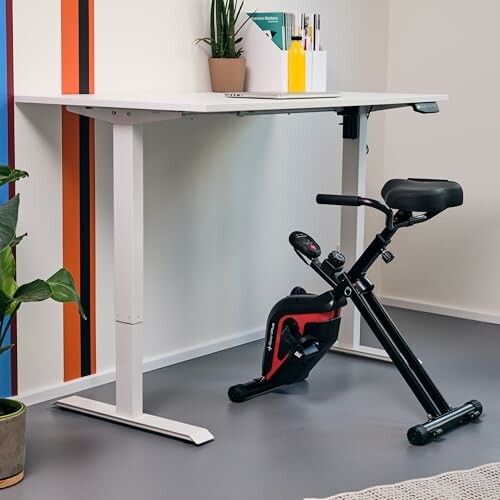 Schreibtisch mit Heimtrainer darunter.