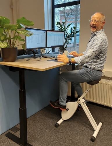 Mann arbeitet auf einem Fahrradschreibtisch.